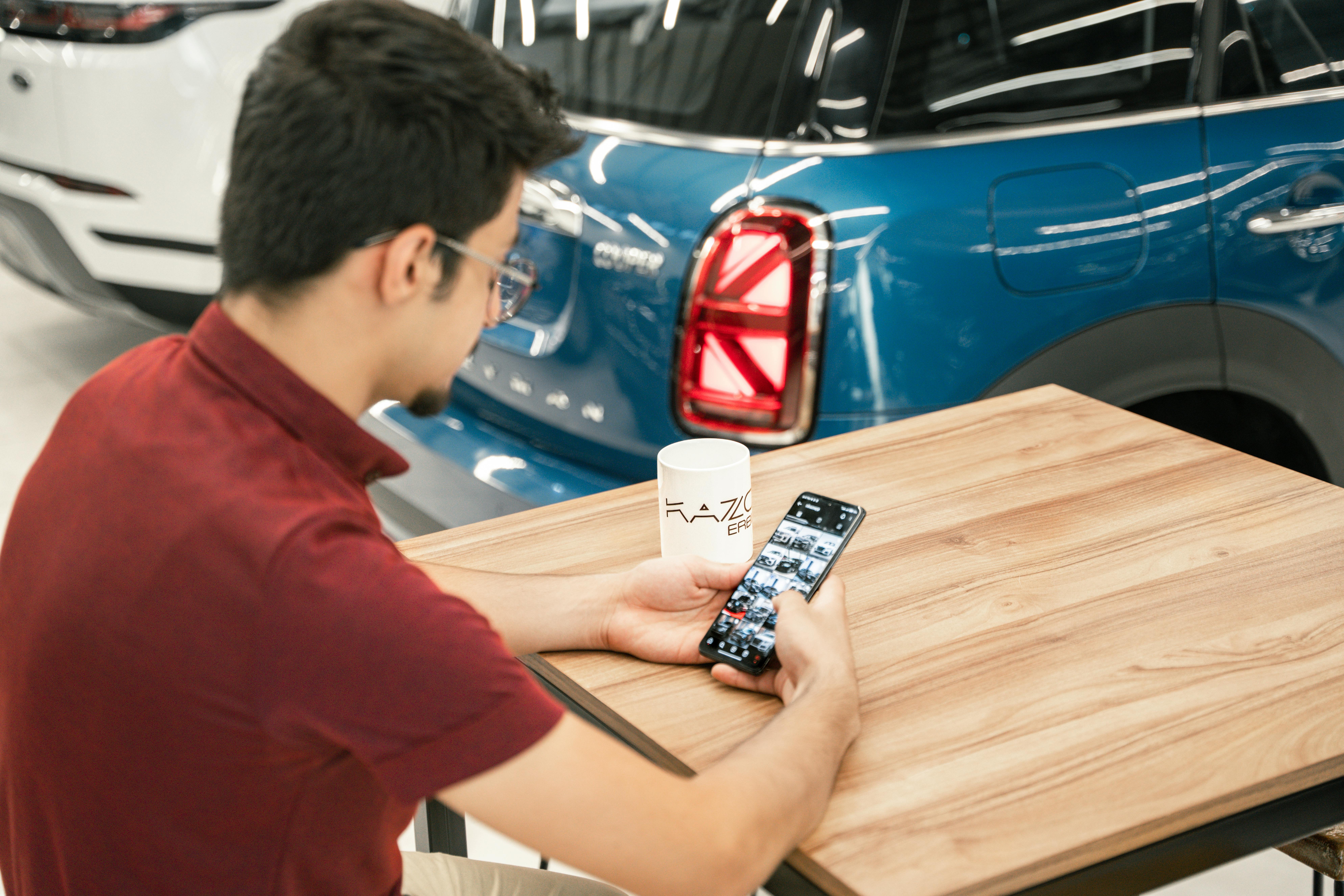 Automobile Dealership IT Support 2 Man browsing through his phone inside a dealership