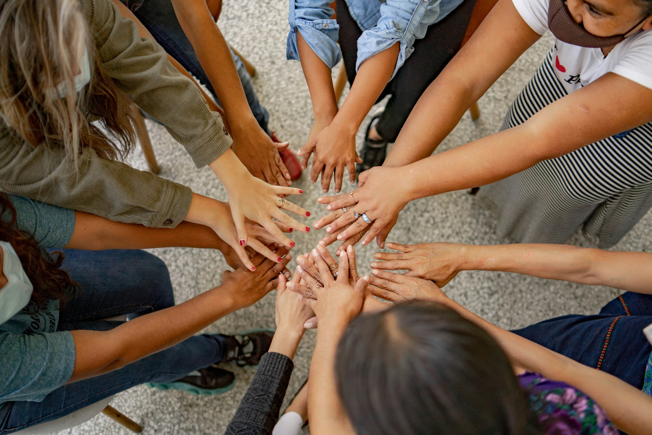 Group of people placing hands together in teamwork circle Group of people placing hands together in teamwork circle