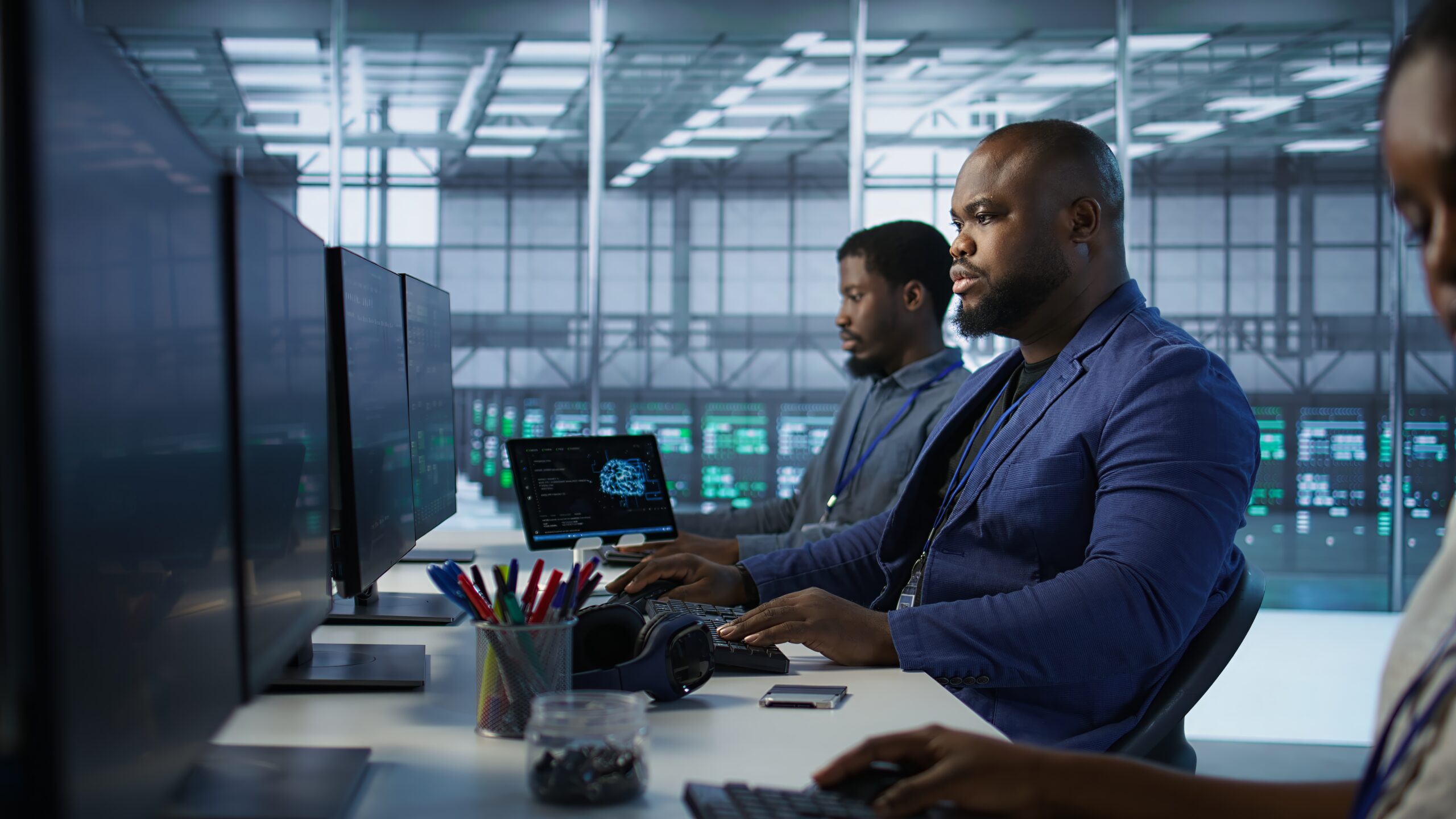 Row of IT specialists working on a desk within server room